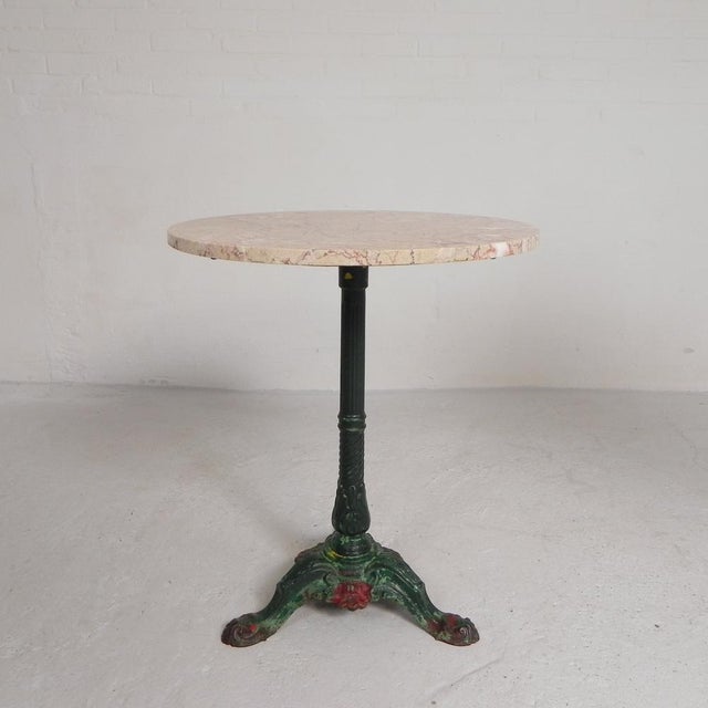 Elegant bistro table from the 1920s with a robust cast iron base and a luxurious marble top. The round marble top is glued...