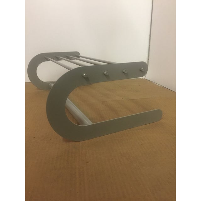 The Stelton Article 6010 is a wall-mounted, powder-coated aluminum hat shelf/hat rack with a rod for hanging clothes....
