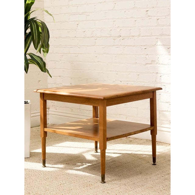 A charming vintage side table featuring a warm wood finish and a practical two-tier design. The square tabletop showcases...