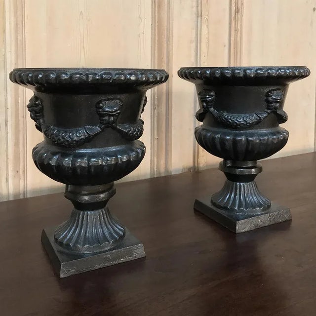 Pair 19th Century Neoclassical Cast Iron Garden Urns are ideal for exterior or interior use. Each is a heavy casting that...