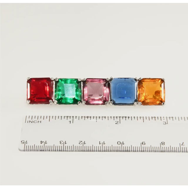 Unmarked large bar pin comprised of beautifully colored jewel tone square unfoiled stones in ruby red, emerald green,...