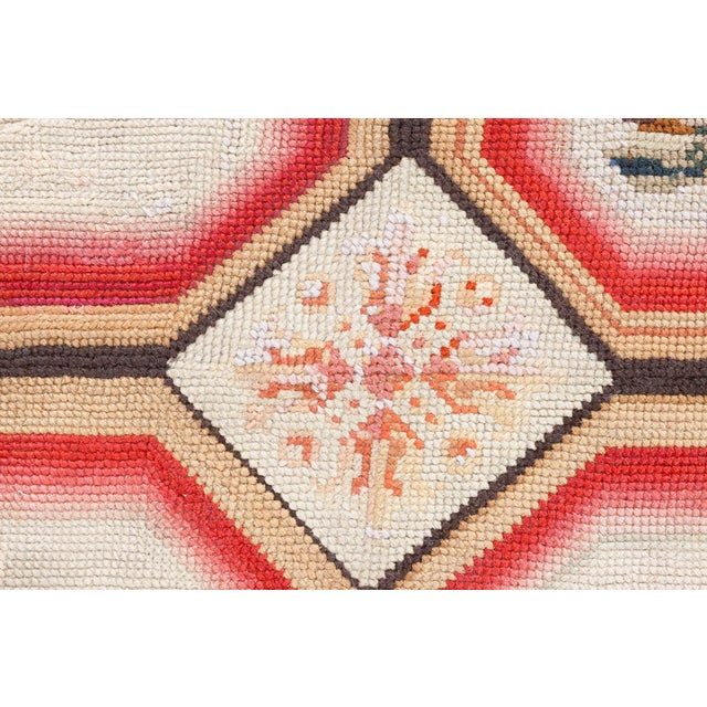 This antique English needlepoint rug, dating back to the early 20th century, is a charming example of traditional...