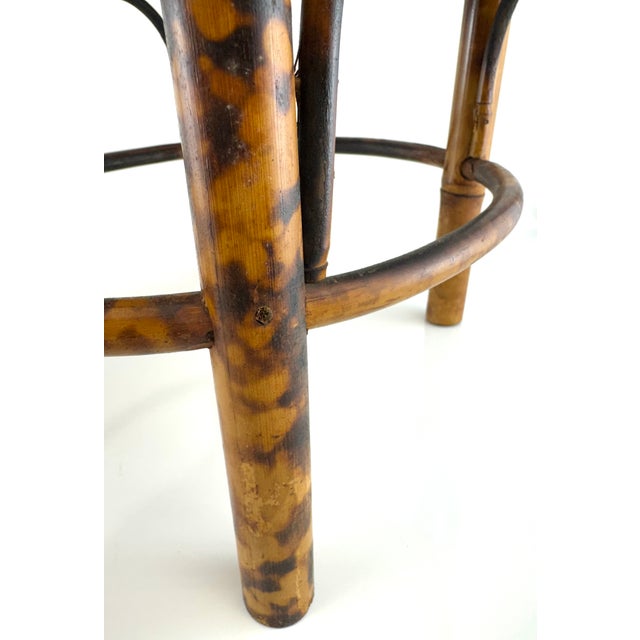 A charming pair of vintage bamboo and rattan plant stands featuring warm tortoiseshell-toned bamboo frames with handwoven...