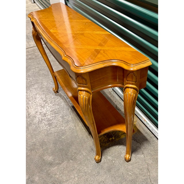 The most striking feature of this table is its tabletop, which boasts a sophisticated patterned inlay. This marquetry...