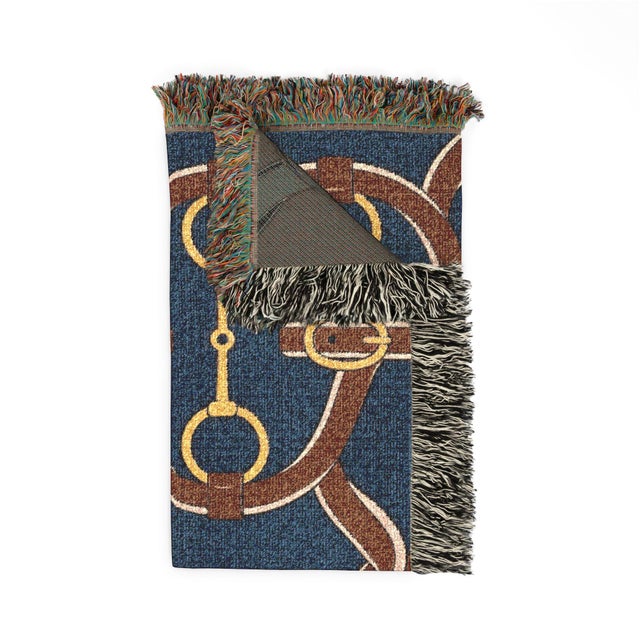 This equestrian woven throw blanket features an oversized bridle and bit pattern in saddle brown, golden yellow, and cream...