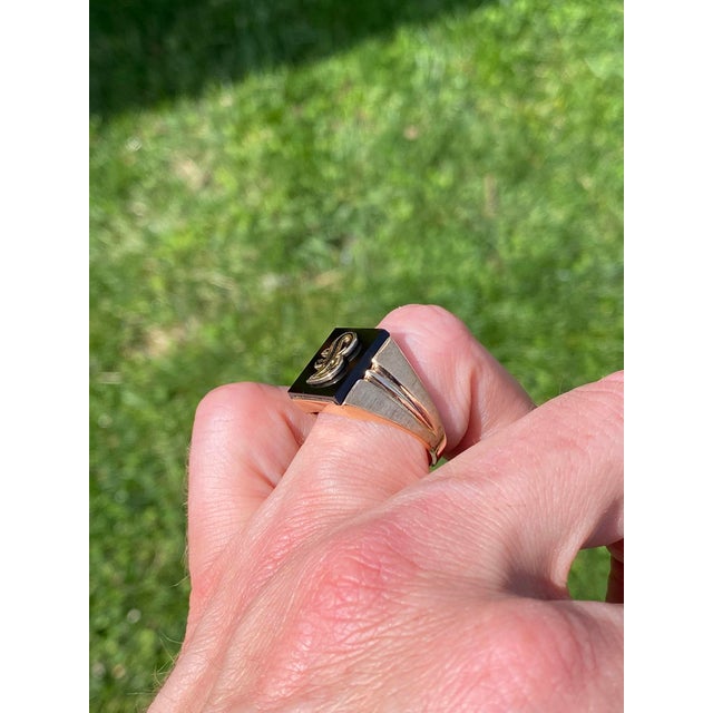 The Jati: Vintage Gentleman's Onyx and Carved J Initial Cocktail Ring in Yellow Gold. This ring features a rectangular...