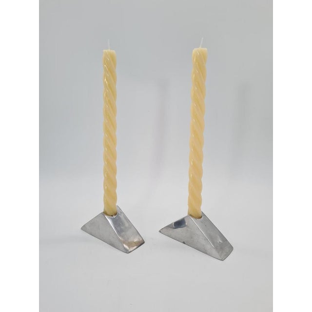 An elegant pair of modernist candlesticks made of polished aluminium, with a distinctly sculptural, geometric form. The...