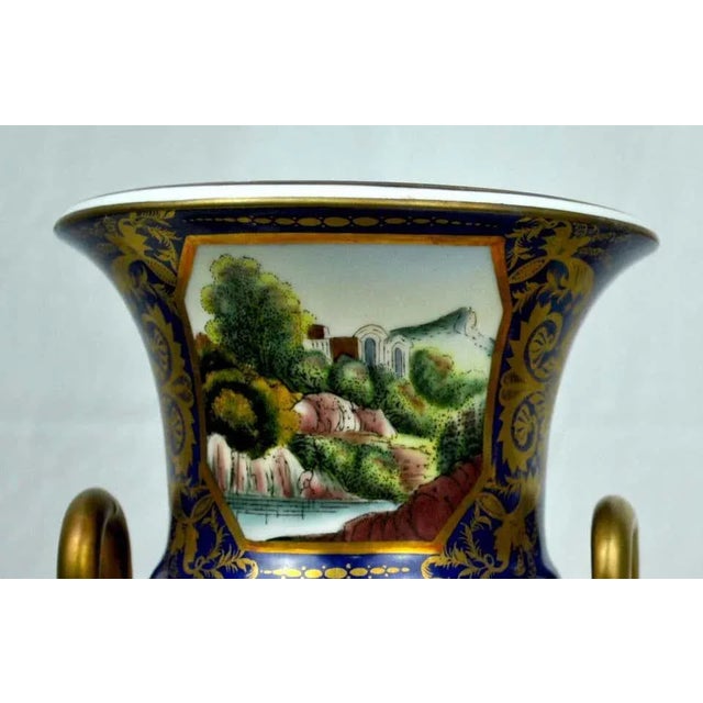 A 20th century pair of deep blue and gold hand painted gilt sieve vases with painted landscape scenes and gilt serpentine...