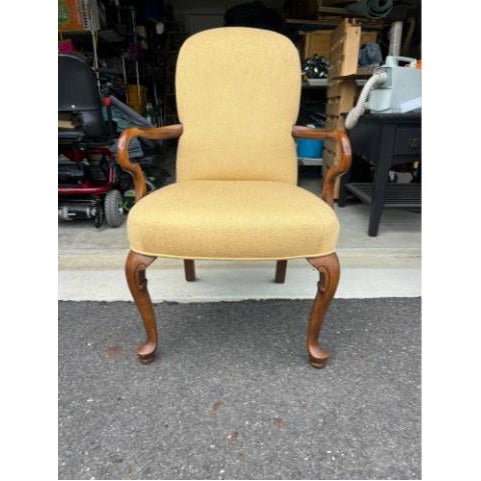 Classic Queen Anne style armchair featuring gracefully curved cabriole legs with carved details and a warm polished walnut...