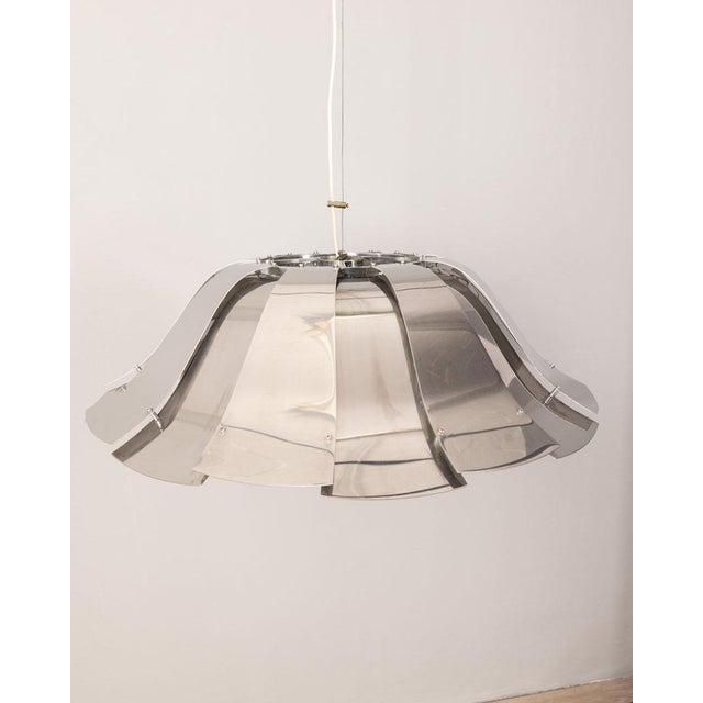 Chandelier with chromed metal elements, a white lacquered lampshade on the bottom, has three lights inside the lampshade...