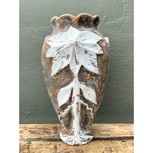 This monumental terracotta vase is a masterclass in rustic elegance, featuring a hand-painted botanical relief that wraps...