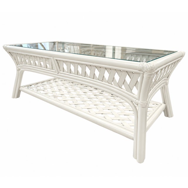 Elegant vintage rattan coffee table featuring a clear glass inset top, intricate diamond-pattern lattice sides, and a...