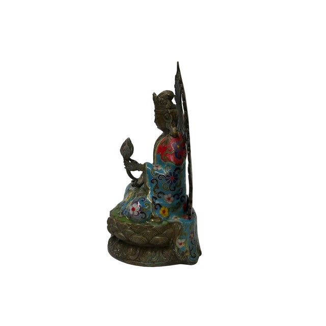 This ornate bronze and cloisonné statue depicts a seated Bodhisattva, likely Guanyin (Avalokiteshvara), captured in a...