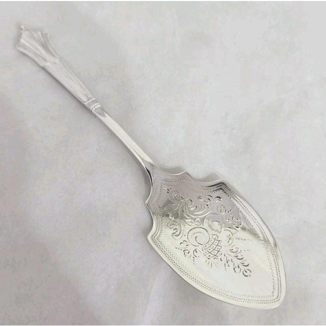 A fine Edwardian sterling silver preserve spoon dating to 1902, displaying elegant decorative craftsmanship characteristic...