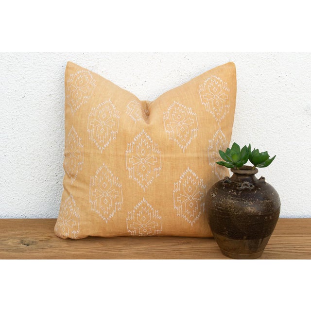 A repeating diamond medallion in crisp white ink covers the full face of this pillow, hand block-printed on golden mustard...