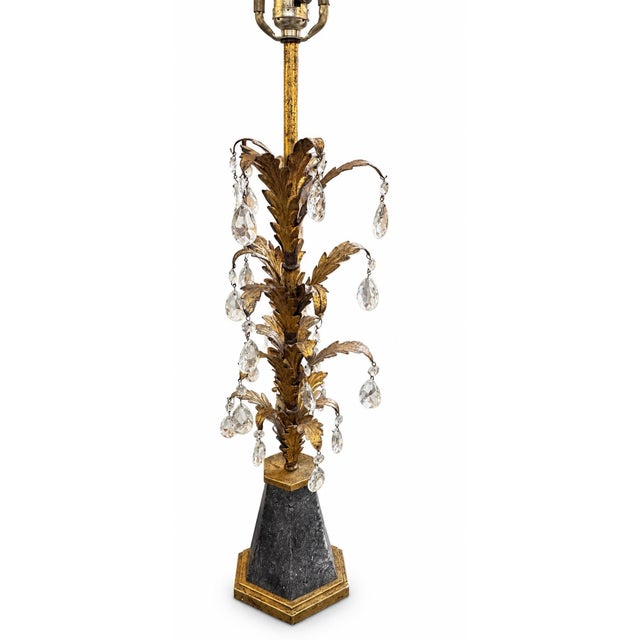 A striking vintage Hollywood Regency table lamp featuring an elaborate gilt-metal botanical form adorned with cascading...