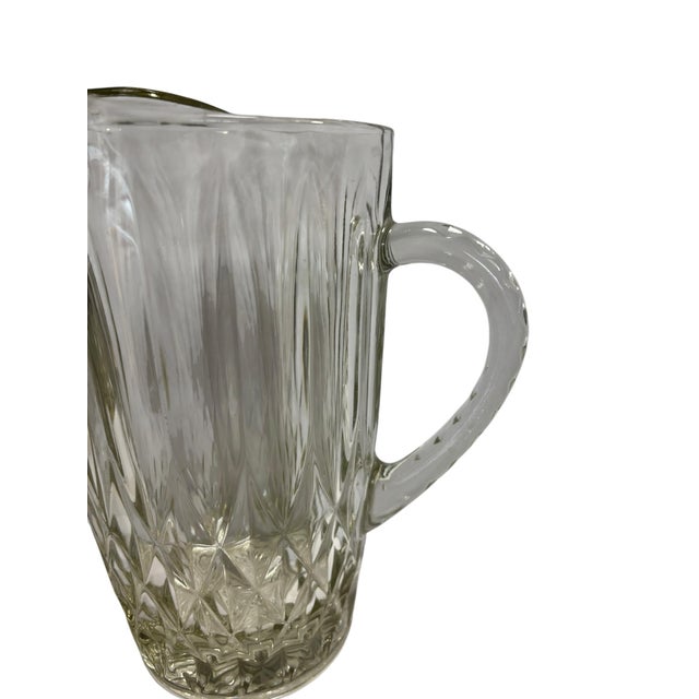 A set of midcentury heavy pressed glass beverage pitcher and 10 low ball glasses. Beverage pitcher 9.5”. Low balls 3.25” H...