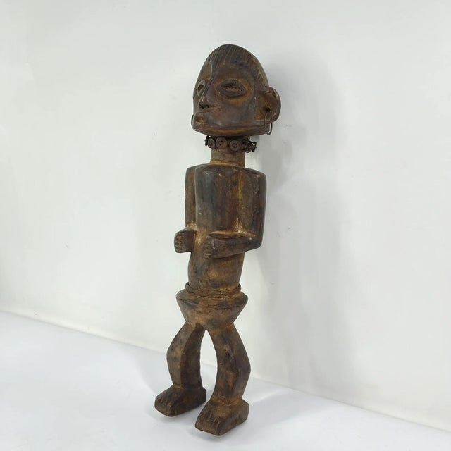The Azande figure was hand-carved by the Azande artisans of the Democratic Republic of the Congo, but the Azande community...