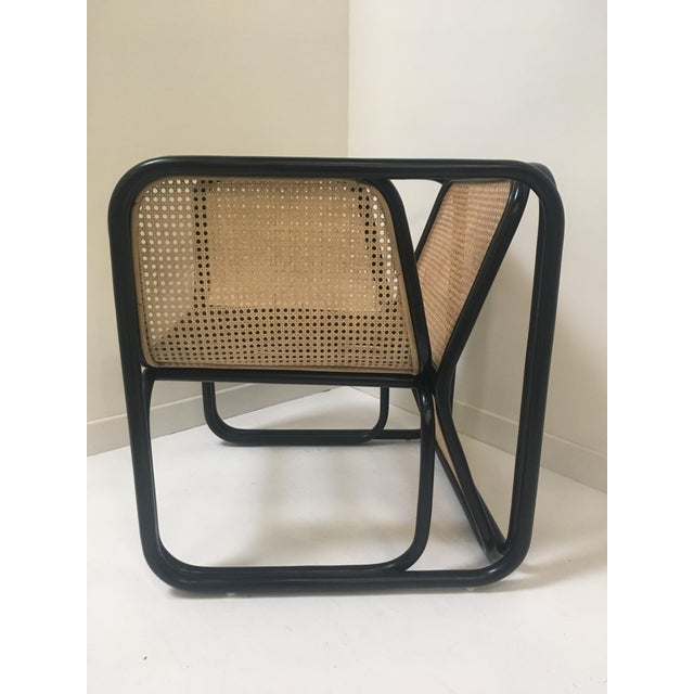 Large armchair in rattan and caning; structure in curved rattan and black lacquered, caned backrest, clean and airy lines.