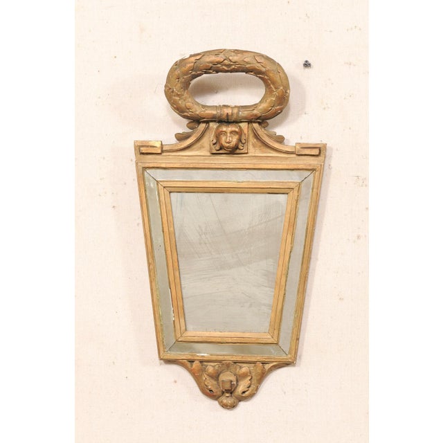 An Italian Neoclassical carved and giltwood mirror from the early 19th century. This elegant antique mirror from Italy...