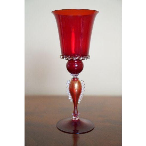 A striking vintage ruby red Murano art glass chalice featuring a tall flared cup, slender stem, round foot, and applied...
