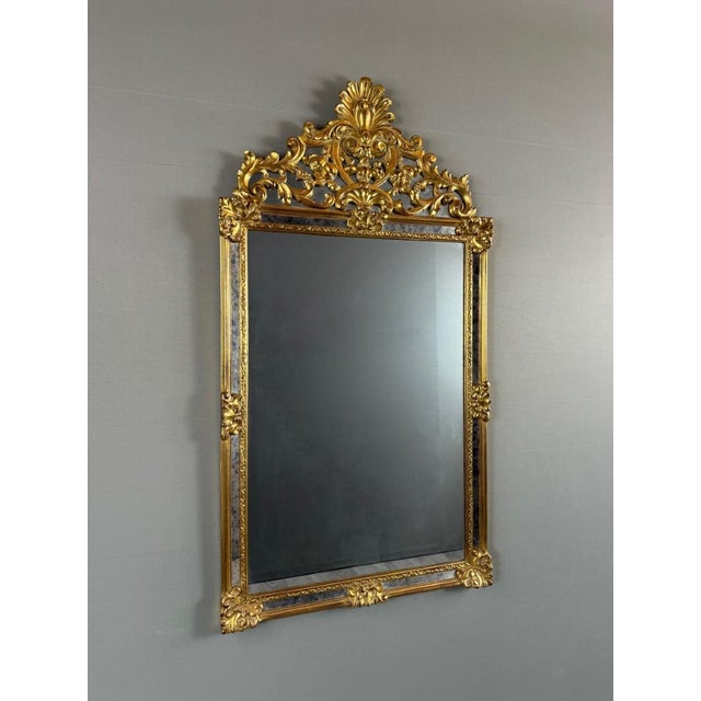 Elegant Louis XV style wall mirror in richly carved and gilded wood, dating from the 20th century. The frame features a...