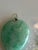 This pendant features a natural green jadeite jade carved into a heart or peach shape. In Chinese culture, this specific...