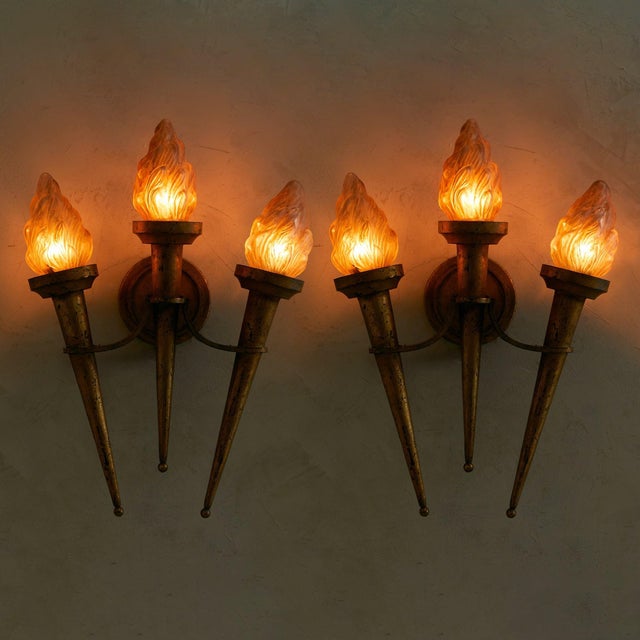 A pair of French sconces from the 1960s, each formed of three elongated torch arms in gilt metal radiating from a circular...