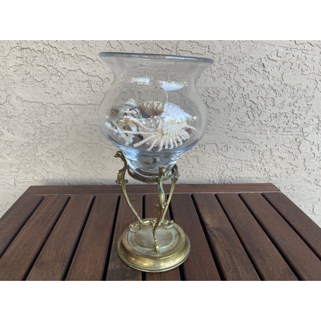 The clear glass vessel is identified as a Blenko product, typically recognized by its hand-blown characteristics and...