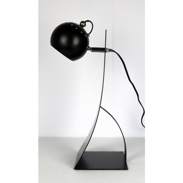 Desk lamp by Brilliant AG, 1990. Black lacquered flat and curved metal base. Adjustable spherical reflector. Chromed metal...