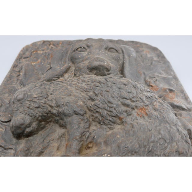 A striking and heavy cast iron relief plaque depicting a hunting spaniel holding a hare, surrounded by an elaborate border...