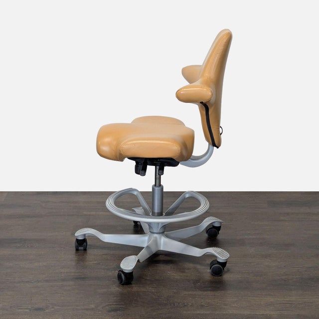 This HÅG Capisco chair features a unique saddle seat design and tan leather finish. The chair offers adjustable height and...