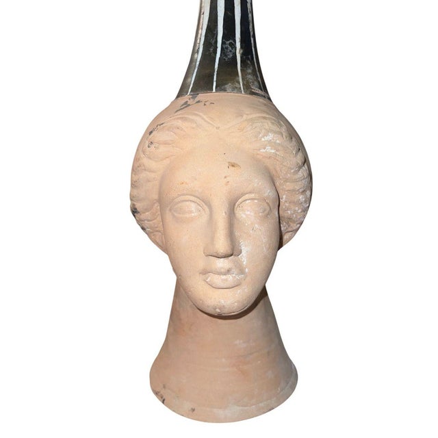 This rare and sculptural Canosan pottery figural oinochoe takes the form of an elegant female head, modeled in terracotta...