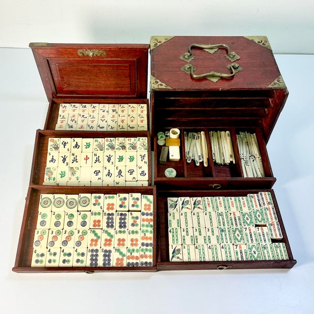 This is a lovely antique Mahjong Game Set. It features tiles that have bamboo backs with bone fronts. The tiles are...