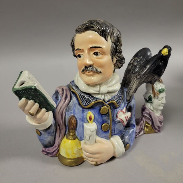 Based on Poe's famous poem "The Raven", this hand painted teapot features Edgar Alan Poe holding a book and a black raven...