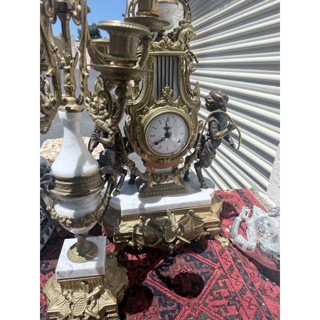 Striking vintage three-piece Imperial clock garniture set consisting of an ornate mantel clock and two matching multi-arm...