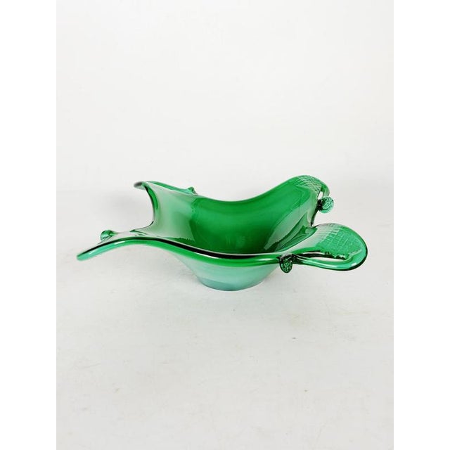 Green glass ashtray, France, 1960s, with a fluid and organic silhouette, typical of glass design from that era. Its free-...