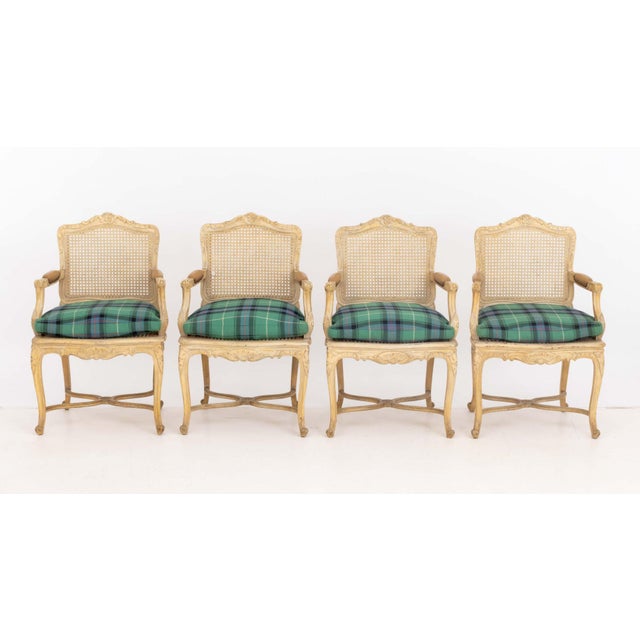 Set of Four Louis XV Style Cane-Paneled Arm Chairs, beige painted wood framed with plaid upholstered cushions and tan...