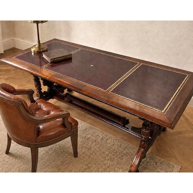 A handsome antique Renaissance Revival library table / writing desk in carved walnut, featuring an inset tooled leather...