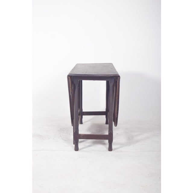 Oval-top table. In dark wood, with an oval top divided into three sections, a fixed centre section and two movable side...