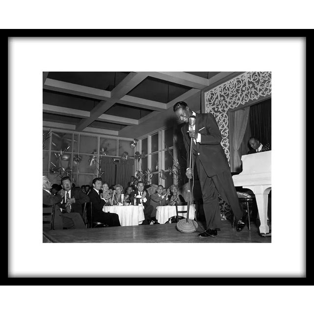 Nat 'King' Cole performing at Ciro's Nightclub in Los Angeles with Jack Palance and Gig Young in the audience, 1954. 11" x...