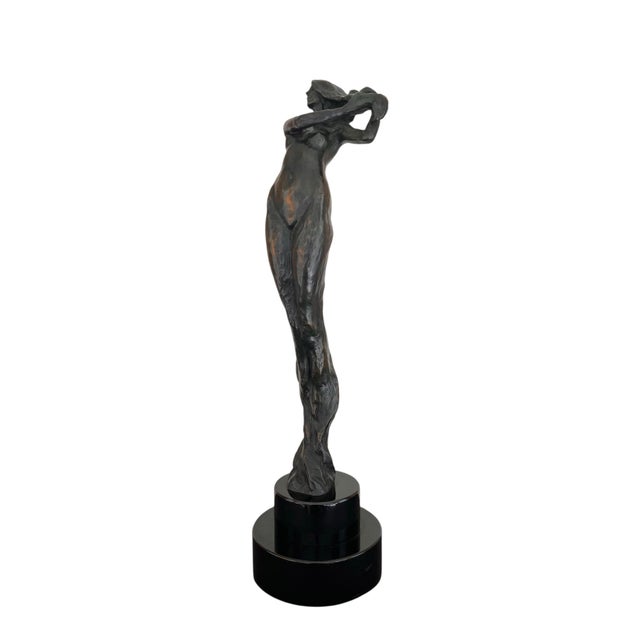 A wonderful bronze figural sculpture on tiered black marble base depicting a woman brushing her hair by noted American...
