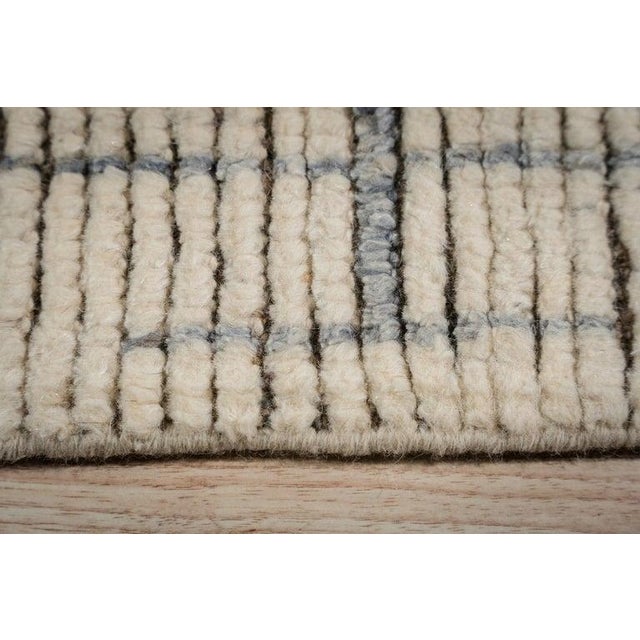 This ivory, beige, and cream wool rug features a hand knotted pile construction. Modeled after traditional Berber carpet...