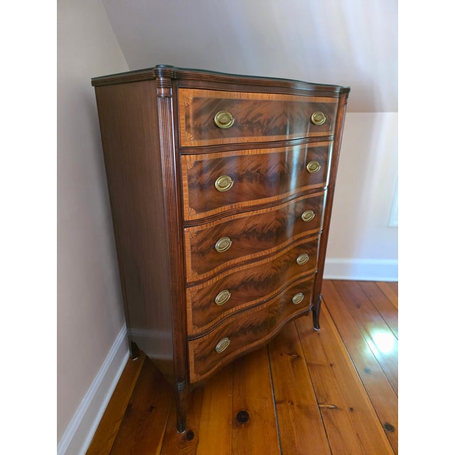 Beautiful early 20th century serpentine shaped chest of drawers with flame mahogany drawer fronts which are accented with...