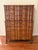 This is a tall wooden chest on chest featuring a dark amber finish, serpentine curved drawer fronts, and brass hardware....
