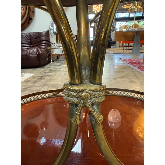 Elegant Italian bar cart from the 1950s featuring two lacquered oval tiers framed by pierced brass galleries. The warm,...