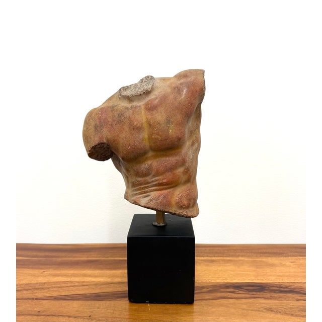 A sculptural study of the male form by Alva, signed and dated 1991. This abstract torso features a textured, earth-toned...