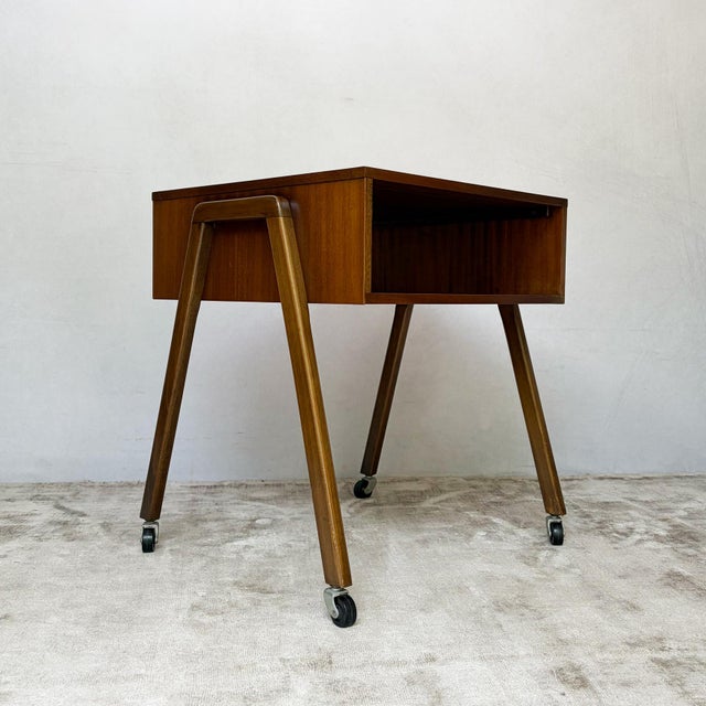 A compact mid century teak cabinet on castors, with an open storage compartment and distinctive splayed legs. The...