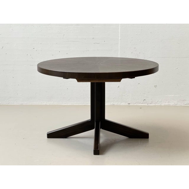 An elegant extendable round table from the swiss manufacturer girsberger, crafted with a dark-stained wood surface using...