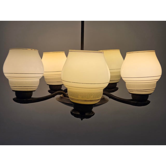 Ceiling lamp designed by Paavo Tynell, model 1376, brass frame, wooden center section, and glass shades. The lamp has...